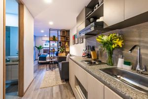 a kitchen with a sink and a living room at Cabrera 85 Apartments in Bogotá