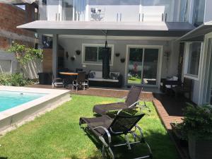 佛羅安那波里的住宿－Casa Luxo com piscina a 500 metros da praia，一个带两把椅子的庭院和一个游泳池