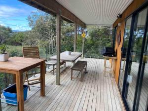 eine abgeschirmte Veranda mit einem Picknicktisch und Bänken in der Unterkunft Rusty Fish in Paihia