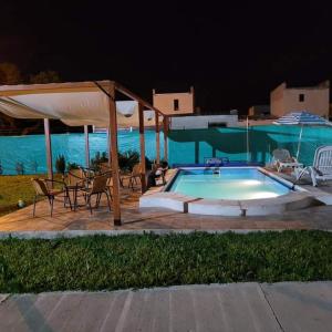 ein Pool in der Nacht mit Stühlen und einem Sonnenschirm in der Unterkunft Cabañas La Estrella in Salta