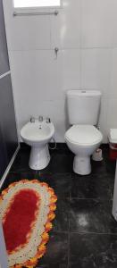 a bathroom with a toilet and a sink and a rug at Cabañas Refugio Verde in El Soberbio