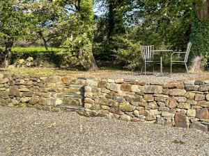 a stone wall with a bench and a table and chair at The Apartment - Uk47181 in Blaenporth