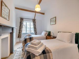 1 dormitorio con 2 camas y chimenea en Grooms Cottage, en Westbury on Severn