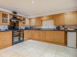 a large kitchen with wooden cabinets and appliances at The Great North Barn - Ukc2526 in Trunch