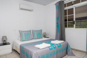 1 dormitorio con 1 cama con almohadas azules y blancas en Fare Piafau - Faa'a Tahiti, en Faaa