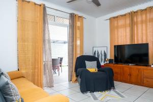 sala de estar con TV y silla en Fare Piafau - Faa'a Tahiti, en Faaa