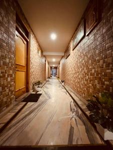 corridoio con pavimento in legno e muro di mattoni di Shakti INN a Rajkot