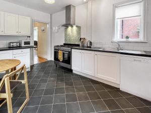 cocina con armarios blancos y estufa negra en Holbeck House, en Scarborough