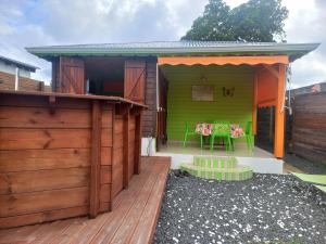 une maison verte avec une table sur une terrasse dans l'établissement Fatou location, à Petit-Bourg