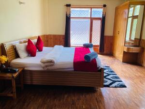 um quarto com uma cama com almofadas vermelhas e uma janela em Jamshi Guest House em Rajkot