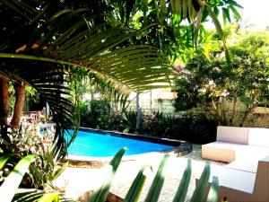 a swimming pool in a garden with a white couch at Giliranta in Gili Trawangan