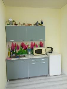 a kitchen with a counter with a microwave and pink flowers at Asian Guest House in Bishkek