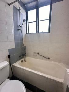 łazienka z wanną, toaletą i oknem w obiekcie AizatAzmi Homestay w Malakce