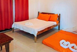 a bedroom with a bed with orange pillows and red curtains at RedDoorz @ Hergem Siargao Inn in General Luna