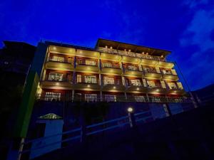 un palazzo alto con luci accese di notte di Krishma Guest House a Rajkot