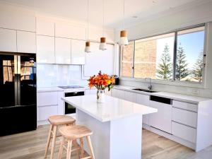 a white kitchen with a white counter and stools at Blue Pacific Apartment 8 in The Entrance