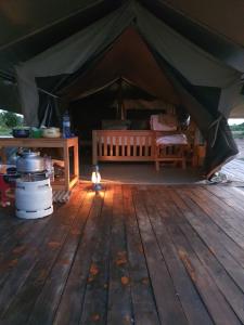 een grote tent met een houten vloer en een tafel bij kabwoya Safari camp Kaiso village in Kisaru