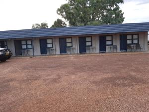 a building with blue doors and chairs in a parking lot at Billabong Hotel Motel in Cunnamulla