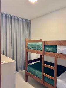 1 Schlafzimmer mit 2 Etagenbetten und einem Schreibtisch in der Unterkunft Praia do Forte - COND ALTO DA ENSEADA - Casa 302 in Mata de Sao Joao