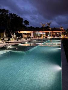 una gran piscina de agua azul por la noche en Praia do Forte - COND ALTO DA ENSEADA - Casa 302 en Mata de Sao Joao
