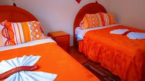 2 camas en una habitación con sábanas de color naranja en HOSTAL ACUARIUS PUNO, en Puno