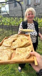 a woman is holding a box of pizza at Cottage and Gigo Papa's Wine Cellar in Kvareli