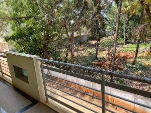a balcony with a fence and a view of a park at Luxury Queen Bed Suite 6km to Palace with Farm Land and Hill View in Mysore