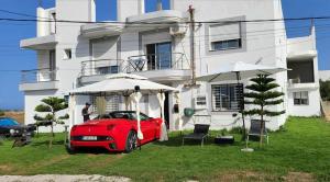 a red car parked in front of a house at Résidence Wissem in Ḩammām al Ghazzāz