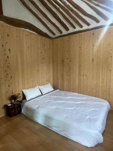 1 dormitorio con cama blanca y paredes de madera en Stay Moon Charm en Gyeongju