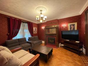ein Wohnzimmer mit Sofa und Fernseher in der Unterkunft THE RED HOUSE in Niagara Falls