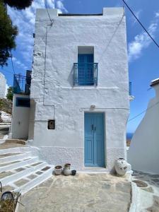 a white building with a blue door on it at School House with Panoramic View in Serifos Chora