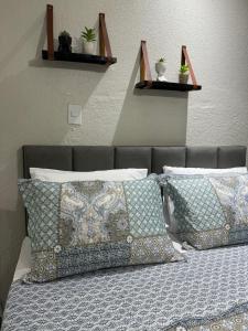 uma cama com almofadas e vasos de plantas na parede em Chalé 04 com cozinha no coração de Penedo em Itatiaia