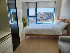 a bedroom with a bed and a large window at Ocean Cloud - Long term Stay in Seogwipo