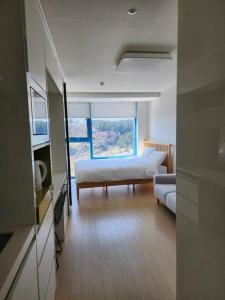 a bedroom with a bed and a couch and a window at Ocean Cloud - Long term Stay in Seogwipo