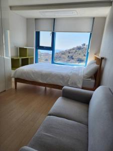 a bedroom with a bed and a large window at Ocean Cloud - Long term Stay in Seogwipo