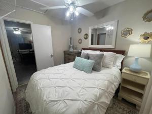 1 dormitorio con 1 cama blanca y ventilador de techo en Bayou Serenity Hideawayfast Wificomfy Bed, en Lake Charles
