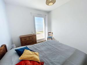 1 dormitorio con 1 cama con ventana y silla en Maison Jullouville, 7 pièces, 10 personnes - FR-1-361-540, en Jullouville-les-Pins