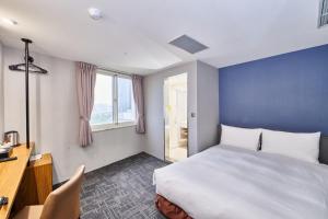 Hotel Leisure 台中輕行旅 في تايتشونغ: غرفة نوم بسرير ومكتب ونافذة