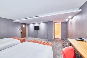 Habitación de hotel con 2 camas, escritorio y TV. en Hotel Leisure 台中輕行旅, en Taichung