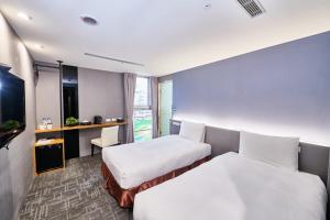 Hotel Leisure 台中輕行旅 في تايتشونغ: غرفه فندقيه سريرين وتلفزيون