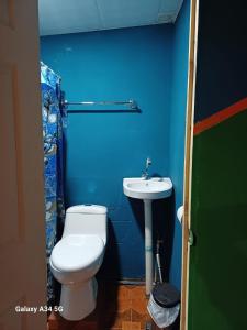 a blue bathroom with a toilet and a sink at Hostal Niña Oly in Tamanique