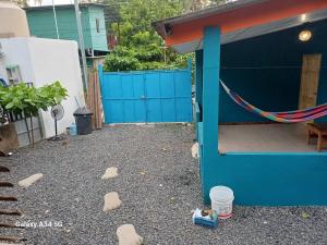 a yard with a blue fence and rocks on the ground at Hostal Niña Oly in Tamanique
