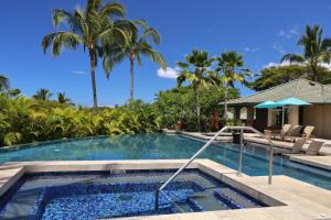 a swimming pool with palm trees in the background at Beautiful Ocean Villa Beautiful Mauna Kea Home with Sunsets and Ocean Views in Hapuna Beach