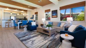 a living room with blue furniture and a kitchen at ORCHID VILLA Inviting Fairways 3BR with Bikes and Private Beach Club in Waikoloa