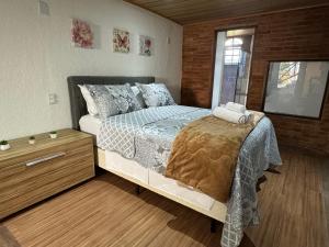 Schlafzimmer mit einem Bett und Holzboden in der Unterkunft Chalé 09 com cozinha no coração de penedo in Itatiaia