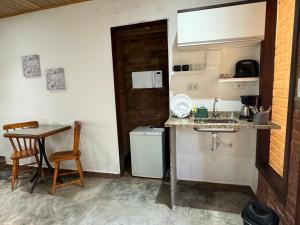 uma pequena cozinha com um lavatório e uma mesa em Chalé 09 com cozinha no coração de penedo em Itatiaia