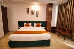 una habitación de hotel con una cama grande y sillas en Sandhu Lodge, en Jamnagar