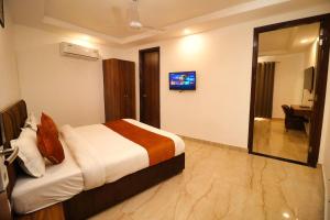 Habitación de hotel con cama y TV en Sandhu Lodge en Jamnagar