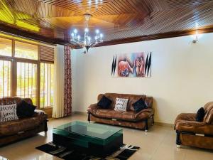 a living room with leather couches and a glass table at Quiet and Spacious Hidden Gem in Kigali with Breathtaking Views right by the Airport in Kigali