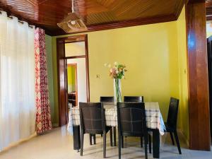 a dining room with a table with chairs and a vase of flowers at Quiet and Spacious Hidden Gem in Kigali with Breathtaking Views right by the Airport in Kigali